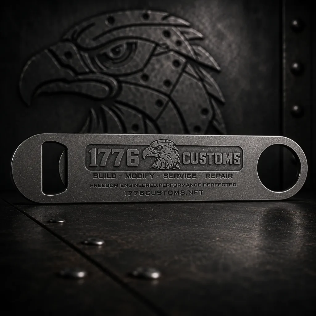 Stainless steel bar blade bottle opener with 1776 Customs logo and eagle emblem on an industrial metal surface.