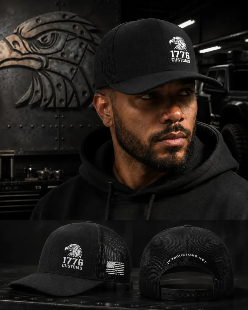 Male model wearing a black 1776 Customs Richardson trucker hat with a ripstop front panel, white eagle logo, mesh back, side American flag patch, and rear snapback closure displaying 1776CUSTOMS.NET.