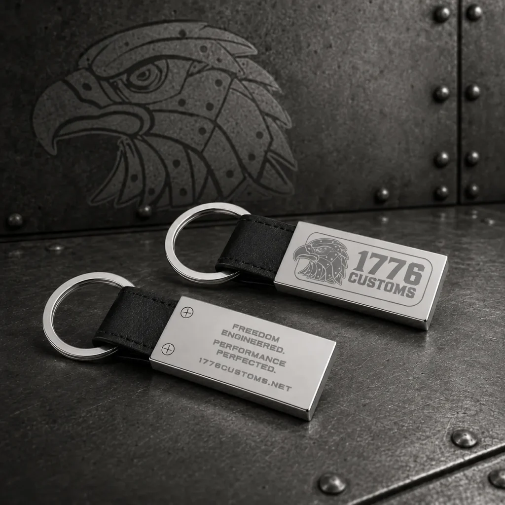 Front and back view of a polished chrome and black leather 1776 Customs key fob on a metal background.