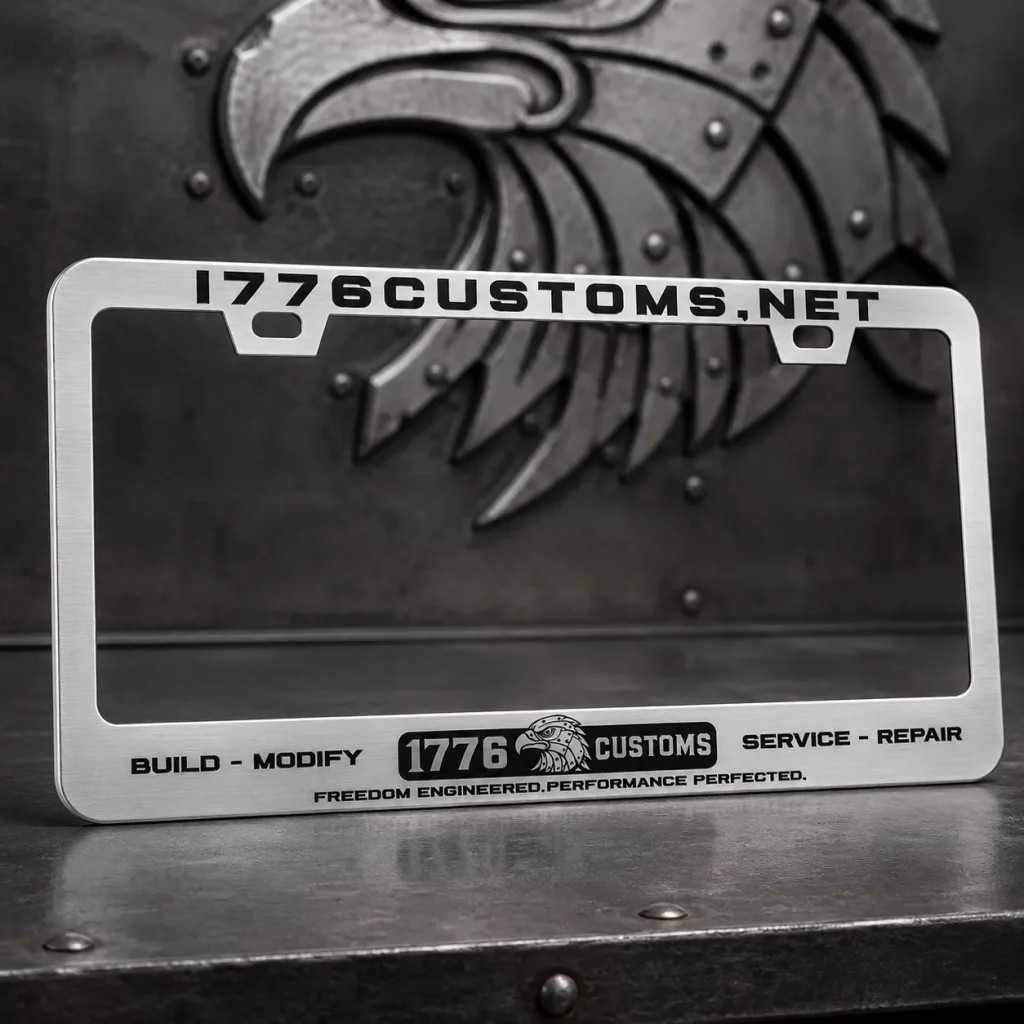 Brushed aluminum 1776 Customs license plate frame with black engraved lettering on a metal surface.